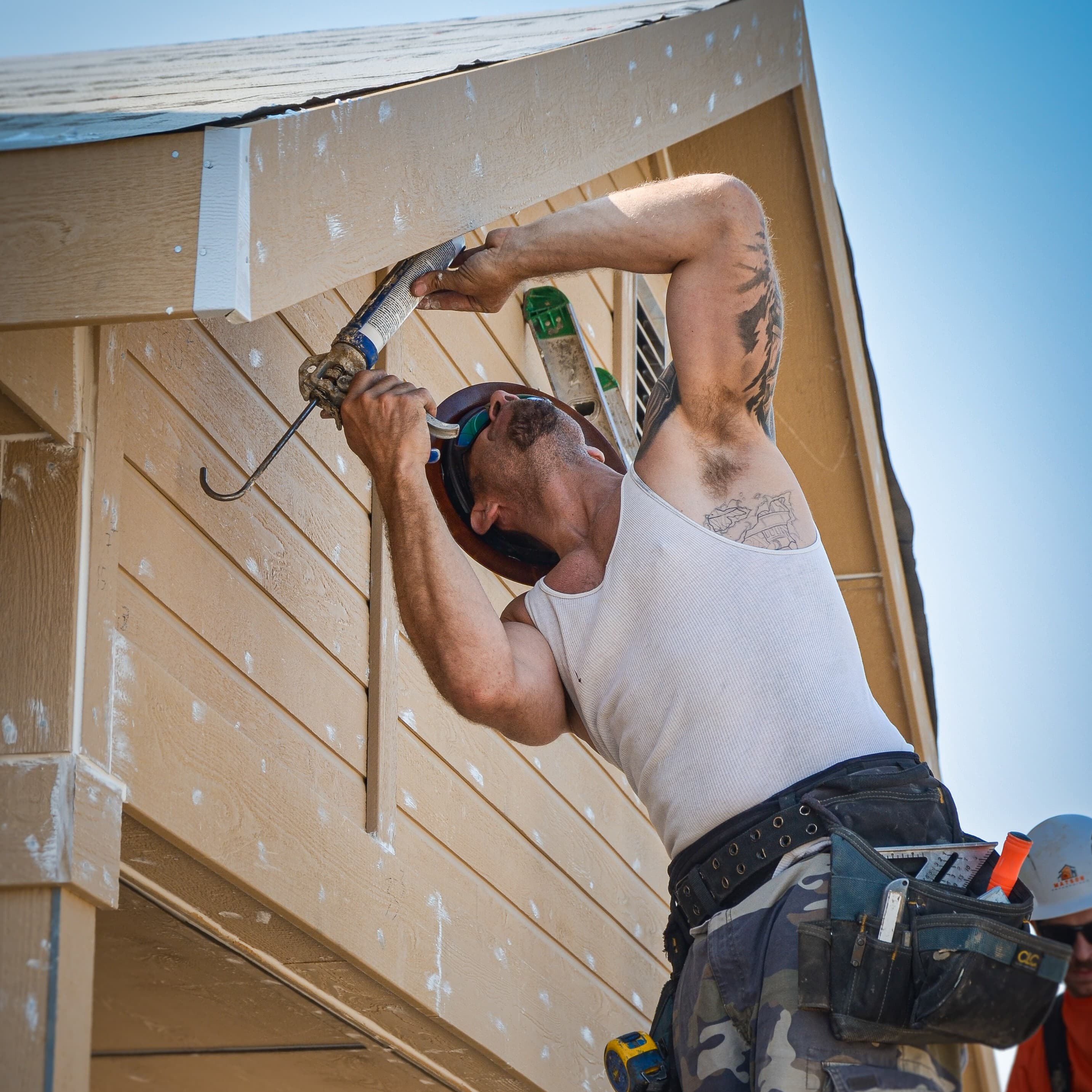 Crew member applying caulk to siding detail